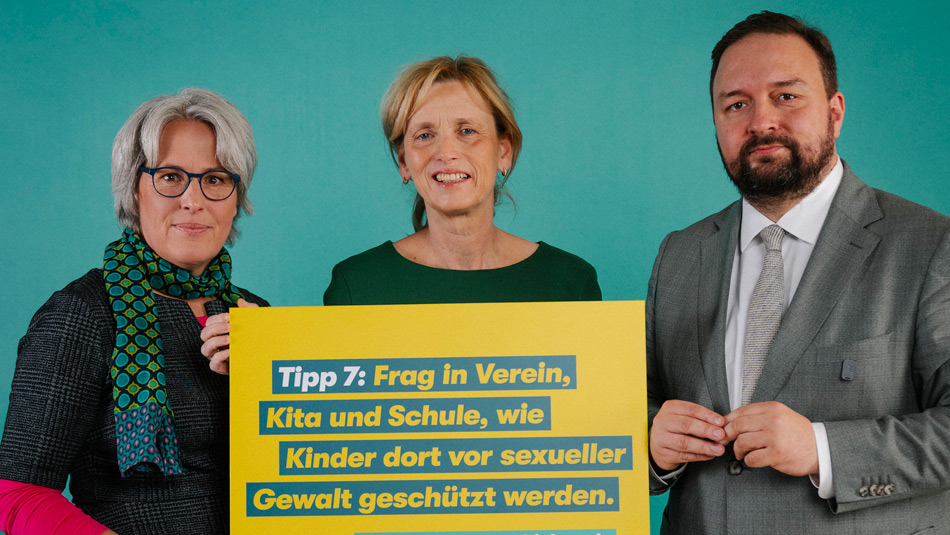 Im Bundestag vor einer neutralen Fotowand und neben Scheinwerfern stehen v.l.n.r. Bundesbeauftragte Claus, Bundesfamilienministerin Prien, MdB Hose, Vorsitzender der Kinderkommission