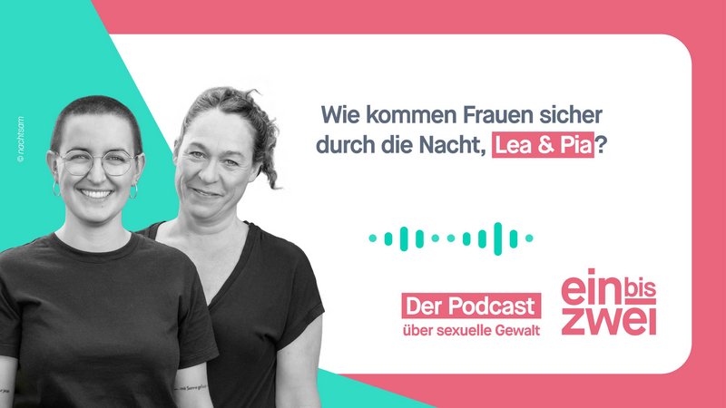 Vor einembegrünten Hintergrund stehen zwei Frauen mittleren Alters in schwarzen T-Shirts hintereinander und schauen lächelnd in die Kamera - die vordere Frau trägt sehr kurzes Haar, die andere hat langes Haar