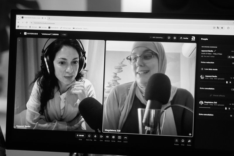 Ein schwarz-weiß-Bild in dem Magdalena Zidi mit Nadia Kailouli in dem Podcast "einbiszwei" spricht.