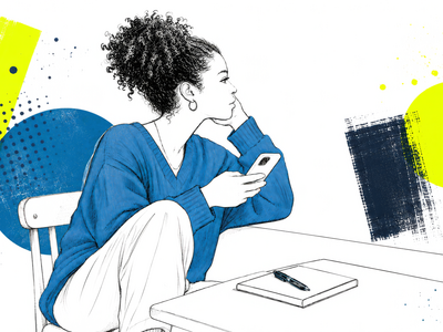 Eine junge Person sitzt an einem Tisch und hält ein Smartphone in der Hand.